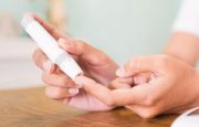 Woman hands using lancet on finger to check blood sugar level by glucose meter