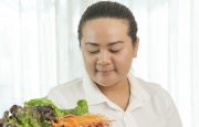 A woman is holding vegetables