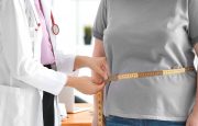 Young female doctor measuring waist of overweight woman with centimeter in clinic